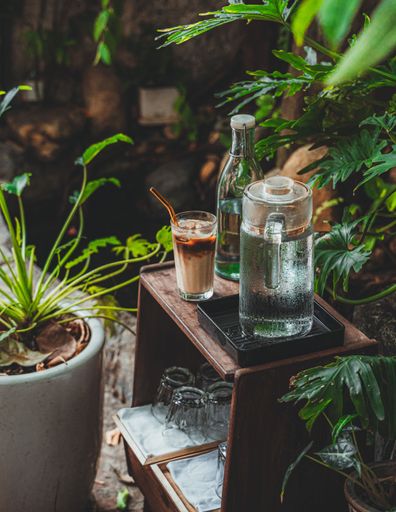 A vertical shot of a wooden cafe table with jugs of water and an iced latte in a cafe