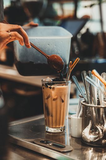 A vertical shot of a person preparing a delicious luxurious iced latte at a cafe