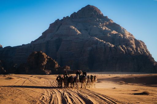 A closeup of people riding Horses in Wadi Rum with a large rock in the background