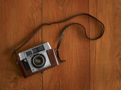 An old camera with strap in wooden background