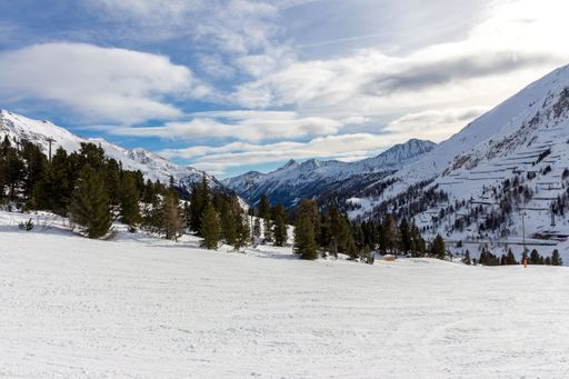 Beautiful winter landscape in the mountains, with a ski slope in the foreground. blue sky with clouds.