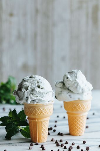 A closeup shot of two waffle cup ice creams on the kitchen counter surrounded by chocolate chips