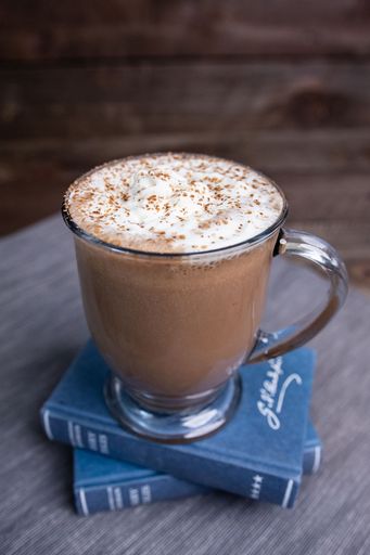 A closeup shot of a glass cup of mocha milkshake topped with whipped cream on the table