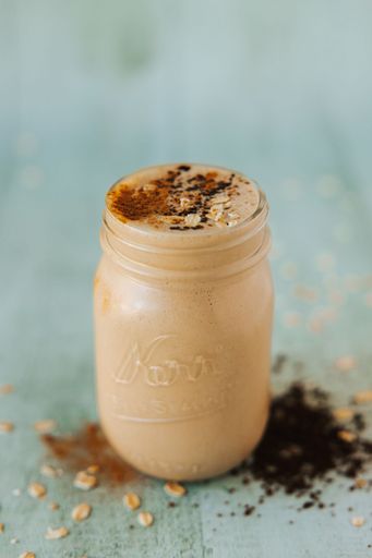 A closeup shot of a glass jar of mocha milkshake topped with cinnamon and cocoa powders