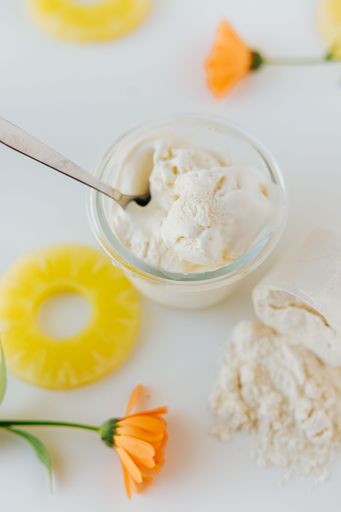 A vertical top view of a glass of ice cream surrounded by sliced pineapples