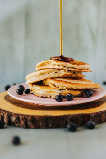 A vertical closeup shot of pancakes on top of each other with blueberries on the plate