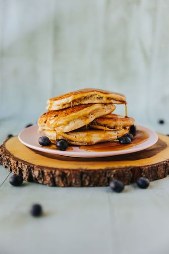 A vertical closeup shot of pancakes on top of each other with blueberries on the plate