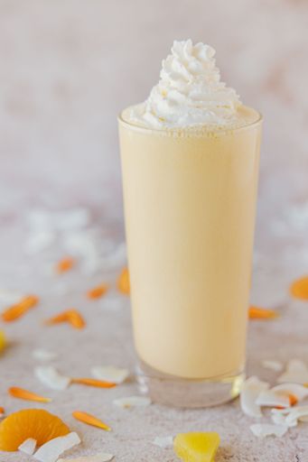 a Selective focus vertical closeup of an Orange Coconut Shake on a marble surface