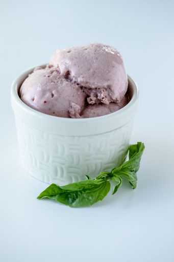 a Vertical high angle shot of a bowl of Tripple Berry Ice Cream against a white background