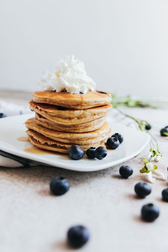 A vertical shot of Blueberry Pancakes with Whipped Cream