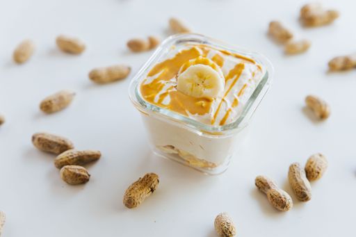 A closeup of a Peanut Butter Banana Mousse in a bowl surrounded by peanuts