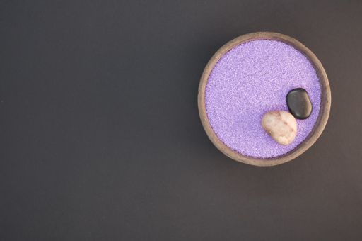 A top view shot of purple sand in a bowl isolated on black background