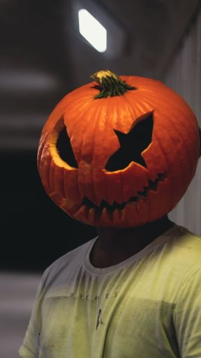 A vertical shot of a man wearing a curved pumpkin on his head