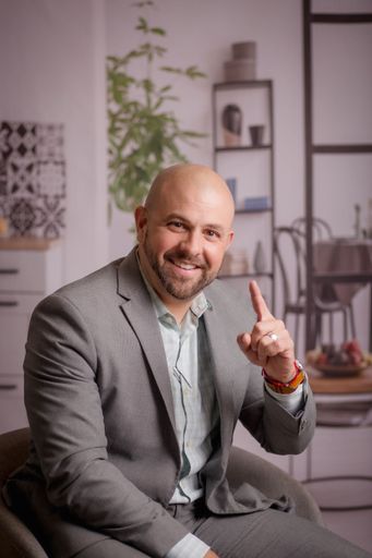 A vertical shot of a smiling succesful businessman in a gray suit with his finger pointing up