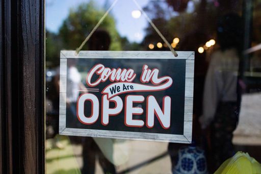 A sign saying "Come in we are open" on window of a store