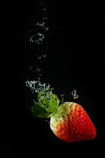 A vertical shot of a red strawberry isolated on a black underwater background