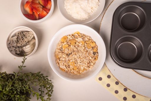 A top view of a table with bowls filled with cereals and strawberries for cooking cookies