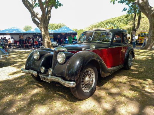 San Isidro, Argentina - Oct 7, 2022: Vintage black and red 1943 Riley RMB 2.5 in a park. Nature, trees. Autoclasica 2022 classic car show.