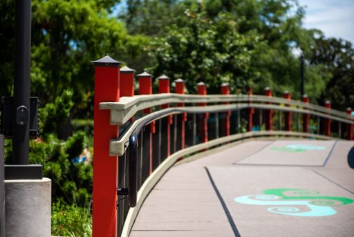 A view of old bridge with red railings passing through leafy park