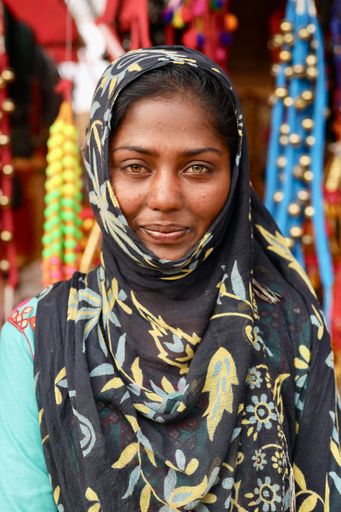A vertical shot of a smiling Indian Kalbelia tribal young girl with a covered head