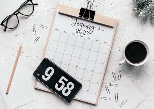 Top view of notepad with January 2023 calendar on table.