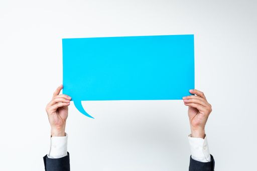 Businessman Holding Speech Bubble With Messages. Man In Suit Presenting Crutial Information On Dialogue Balloon. Gentleman Showing On Paper.