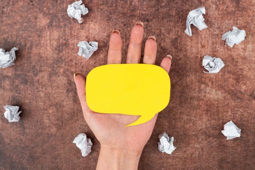 HOf Businesswoman Holding Speech Bubble Made Of Sheet With Copy Space With Crumpled Papers Over Wood. Blank Space For Business Advertisement Branding.
