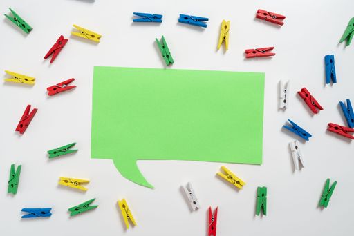 Colorful Pegs Placed Around Speech Bubble With Information. Wooden Clips Arranged All Over Dialogue Ballon With Idea. Pins With Critical Data Inside.