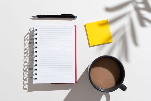 Notebook With Messages On Desk With Coffee, Notes And Pen. Information Written On Pad On Table With Cup, Memos And Pencil. Late Updates Presented.