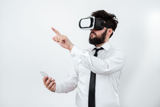 Man Holding Phone, Wearing Vr Glasses And Pointing On With One Finger. Businessman Having Virtual Reality Eyeglasses, Cellphone And Presenting Idea.