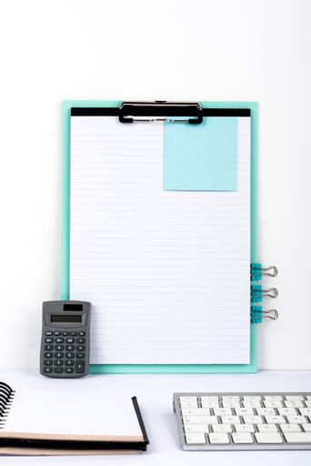 Message Presented On Clipboard On Desk With Notebook, Paperclips, Calculator And Keyboard. Information Written On Paper On Table With Notepad.