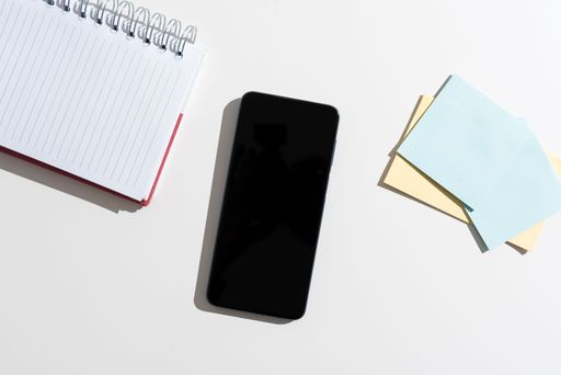 Mobile Phone With Message On Desk With Empty Notebook And Notes. Cellphone Screen With Crutial Information On Table With Notepad And Memos.