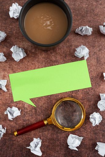 Speech Bubble Made Of Sheet With Magnifying Glass, Coffee Cup Surrounded With Crumpled Papers Over Wooden. It Is Presenting Analyzing Of Plans 