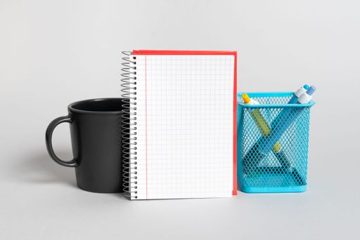 Cup, Notebook With Message And Pencil Case On Desk. Mug, Note With Information And Pens. Glass, Critical Announcement Written On Paper And Pencils.
