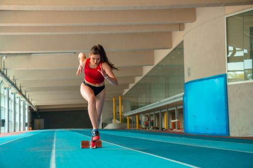 A vertical shot of a sprinter woman running at a gym