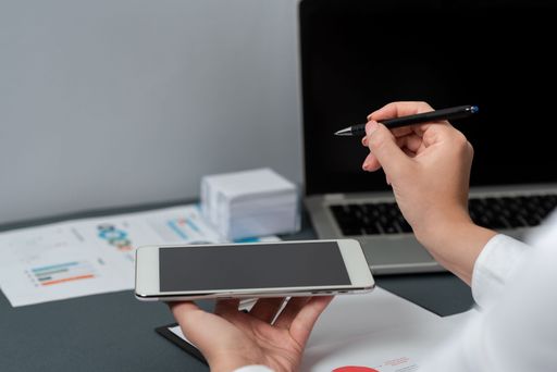Businesswoman Holding Phone And Pen Pointing On Message. Woman In Suit Having Pencil In Hand And Presenting Information. Executive Showing Idea