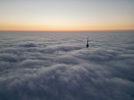 A beautiful view of A cityscape with the CN Tower in dense fog in Toronto with sunset sky