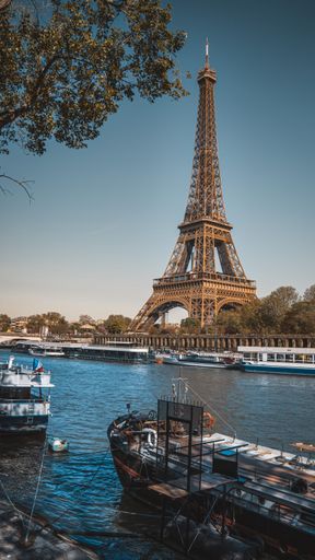 A beautiful view of the Eiffel Tower with boats on a river