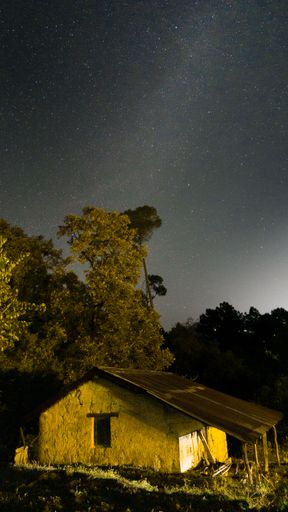 A vertical shot of the old house like construction against a starry night sky