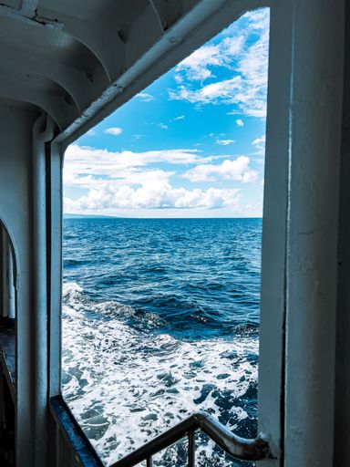 A view from a ship of the sea with blue cloudy sky in the daytime
