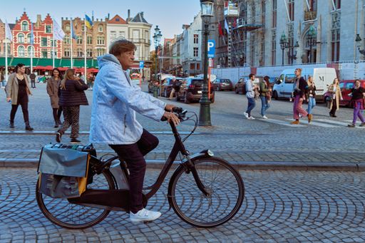 A woman cycling through the main square of Bruges in Belgium on an autumn morning