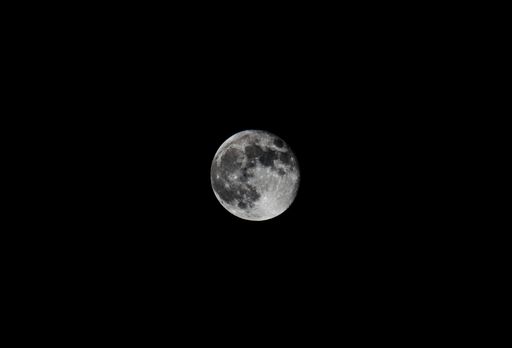 A scenic closeup of the full moon in the black night sky, cool for background