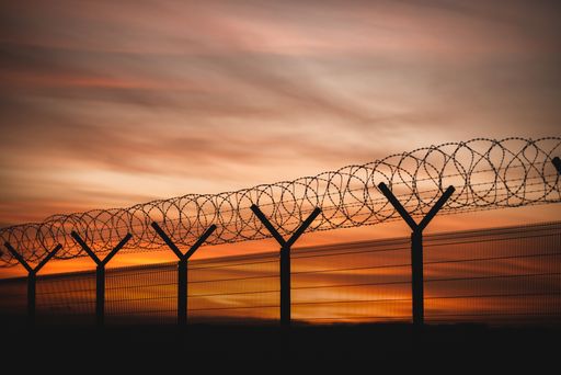 A closeup of a barbed fence against the vivid sunset sky