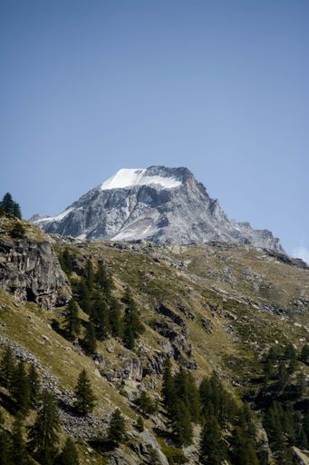 A vertical shot of the rocky mountain peak against the background of the blue sky.