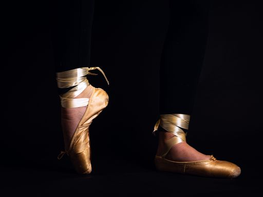 A low section of ballet dancer dancing against black background