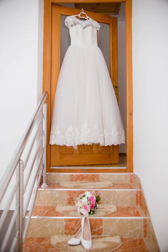 A vertical shot of the bride's beautiful wedding dress hanging from a door