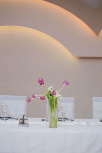 a vertical shot of purple flowers in a transparent pot on a restaurant table with dishware