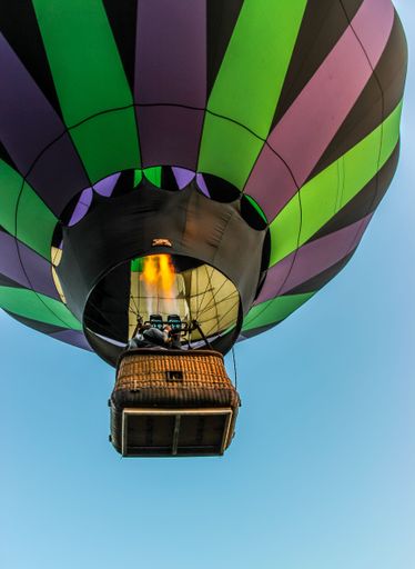 A low-angle shot of the colorful hot-air balloon floating in the air against the blue clear sky