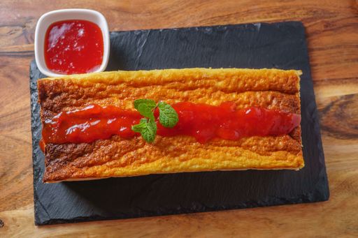 cheesecake with strawberry jam and mint leaves on a black board