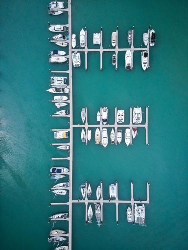 A drone sot of the moored yachts and boats in a harbor on a sunny day